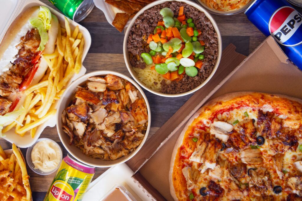 A variety of fast food items including pizza, sandwiches, and fries with drinks, perfect for a hearty meal.