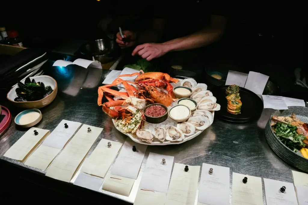 Luxurious seafood platter with lobster and oysters prepared in a restaurant kitchen.