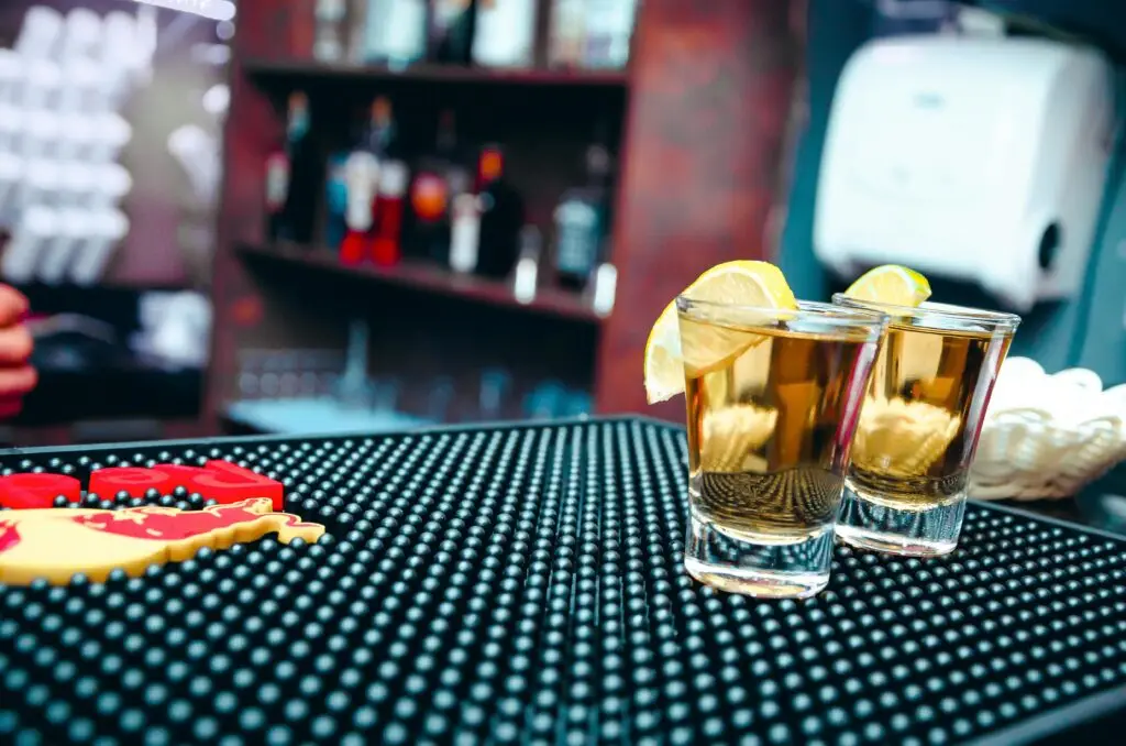 Close-up of tequila shots with lemon slices at a bar, ideal for nightlife scenes.
